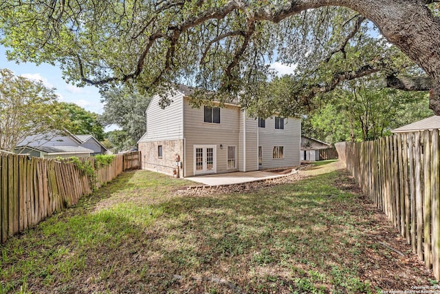 rear view of house with french doors, a lawn, a patio area, and a fenced backyard