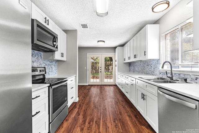 kitchen featuring stainless steel appliances, a sink, light countertops, and white cabinetry