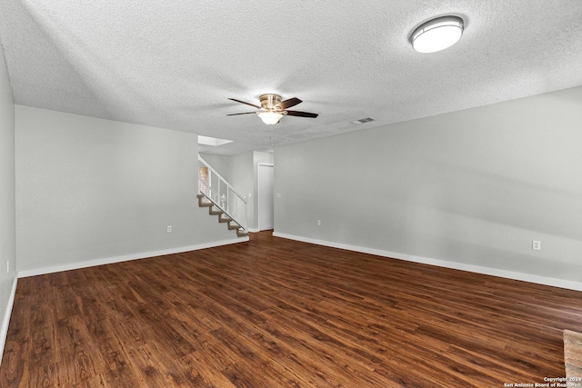 unfurnished room with visible vents, dark wood finished floors, stairway, and ceiling fan