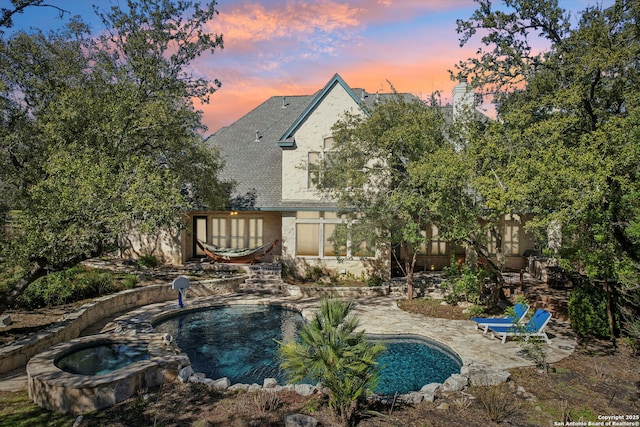 exterior space with a patio area, a pool with connected hot tub, and stucco siding