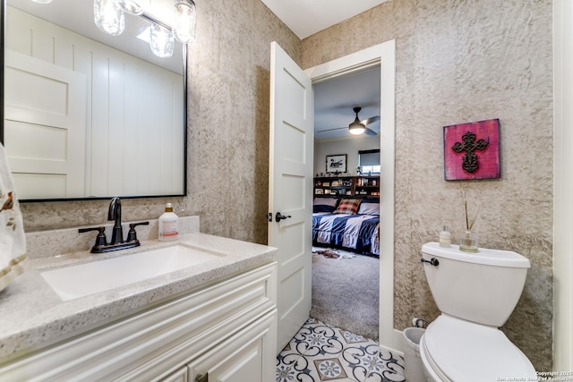 ensuite bathroom featuring toilet, wallpapered walls, connected bathroom, and vanity