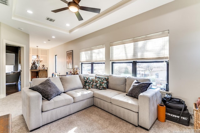 living room featuring ceiling fan with notable chandelier, visible vents, a raised ceiling, and recessed lighting