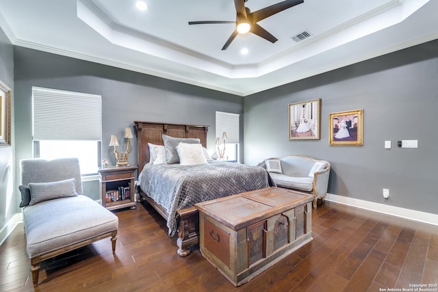 bedroom featuring a tray ceiling, dark wood-type flooring, visible vents, and baseboards