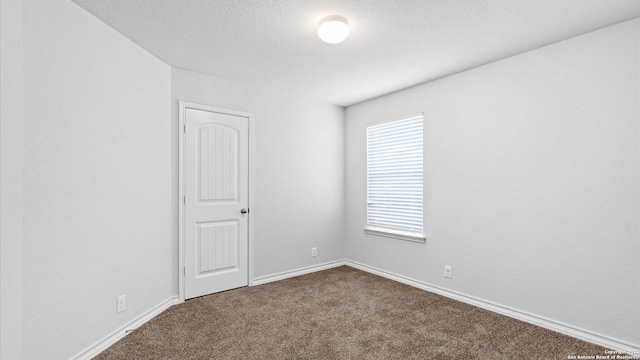 unfurnished room with carpet, a textured ceiling, and baseboards