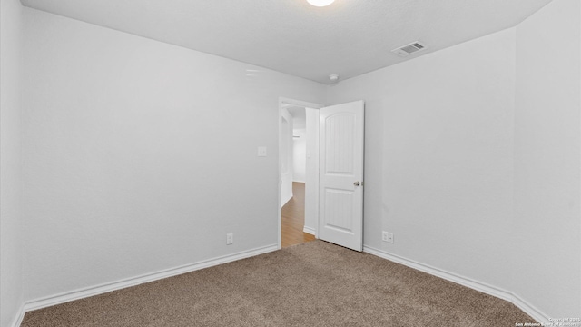 carpeted spare room featuring visible vents and baseboards