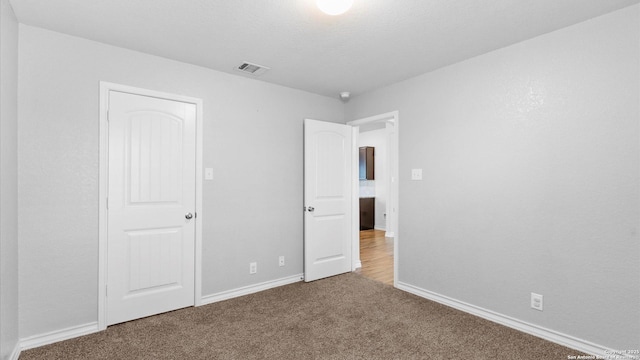 unfurnished bedroom featuring carpet flooring, visible vents, and baseboards