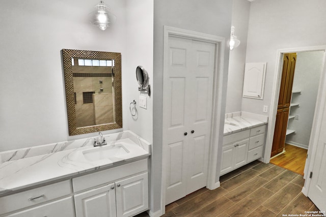 full bath with tiled shower, a closet, wood finished floors, and vanity