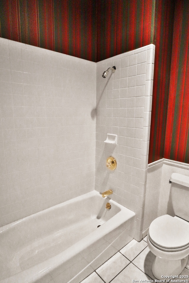 bathroom with toilet, wallpapered walls, tile patterned flooring, and shower / tub combination