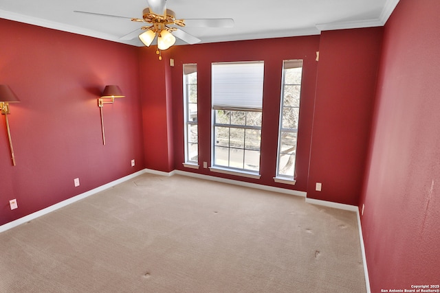 empty room with baseboards, ornamental molding, a ceiling fan, and light colored carpet