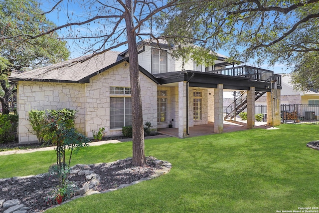 back of property with roof with shingles, a lawn, a wooden deck, and stairs