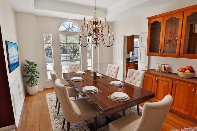 dining room featuring light wood-type flooring, crown molding, a tray ceiling, and a notable chandelier