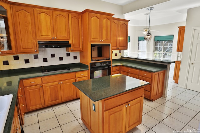 kitchen featuring dark countertops, under cabinet range hood, a kitchen island, and black appliances