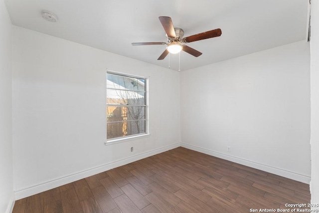 empty room with dark wood-style floors, baseboards, and a ceiling fan