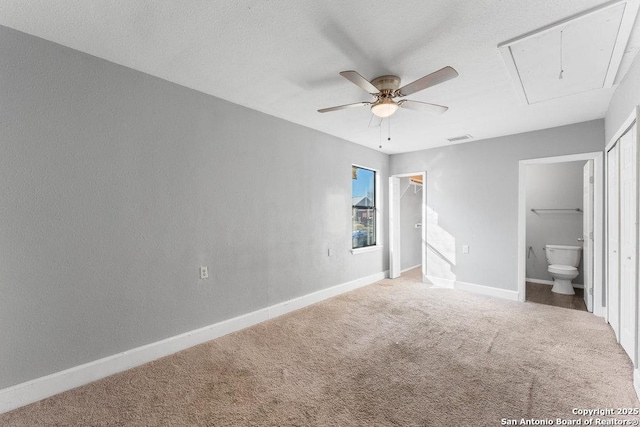 unfurnished bedroom with attic access, visible vents, baseboards, ensuite bath, and carpet flooring