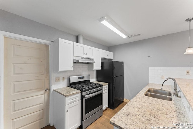 kitchen featuring stainless steel gas range oven, visible vents, white cabinets, under cabinet range hood, and pendant lighting