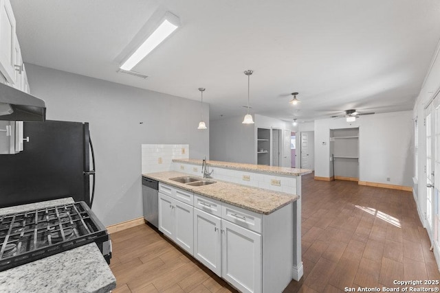 kitchen featuring a peninsula, a sink, freestanding refrigerator, and white cabinets