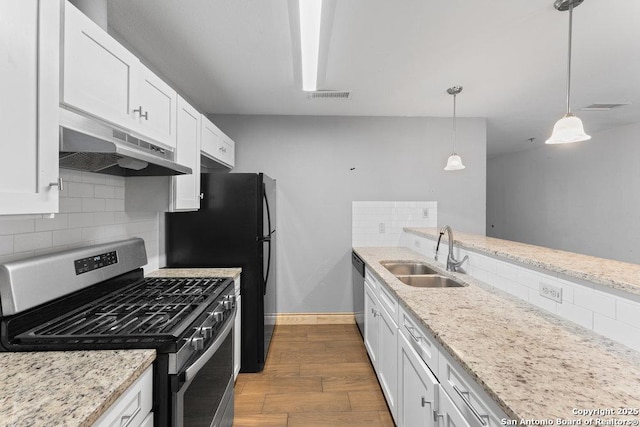 kitchen featuring white cabinets, decorative light fixtures, stainless steel appliances, under cabinet range hood, and a sink