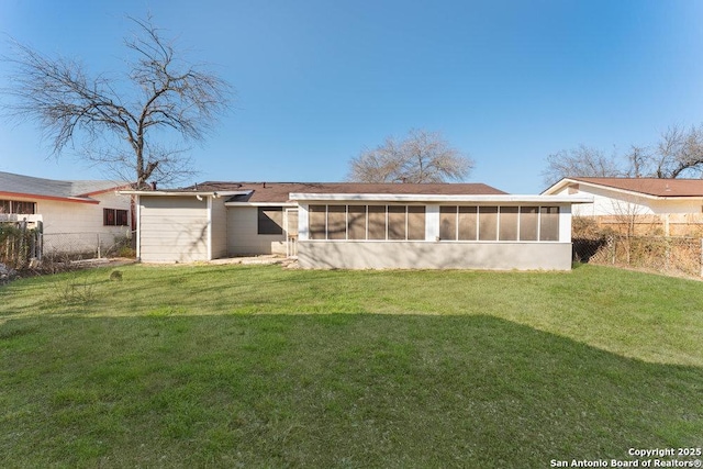 rear view of property featuring a yard, fence, and a sunroom