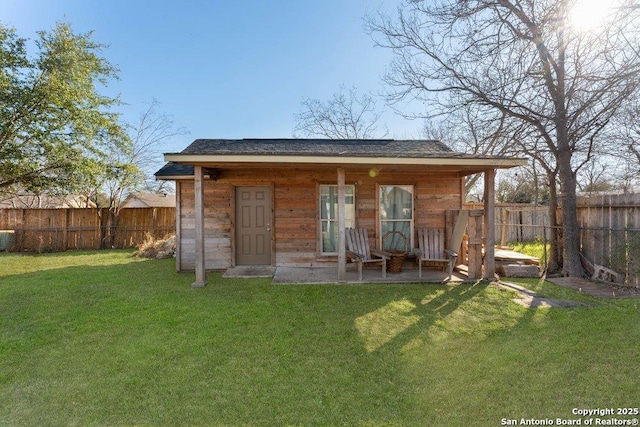 back of property featuring a fenced backyard, a lawn, and an outbuilding