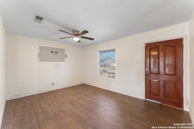 empty room featuring ceiling fan, dark wood-style flooring, visible vents, and baseboards