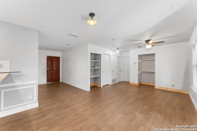 unfurnished living room featuring visible vents, baseboards, and wood finished floors