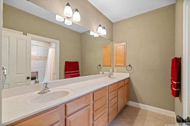 bathroom featuring baseboards, double vanity, a sink, and tile patterned floors