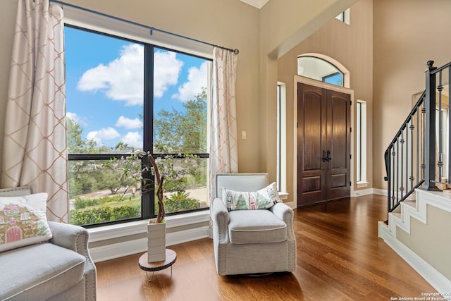 entryway featuring a high ceiling, stairway, wood finished floors, and baseboards