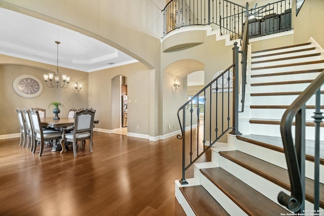 entrance foyer with dark wood-style flooring, stairway, baseboards, and an inviting chandelier