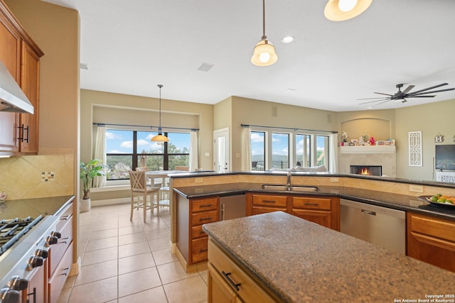 kitchen with brown cabinets, stainless steel appliances, dark countertops, tasteful backsplash, and a sink