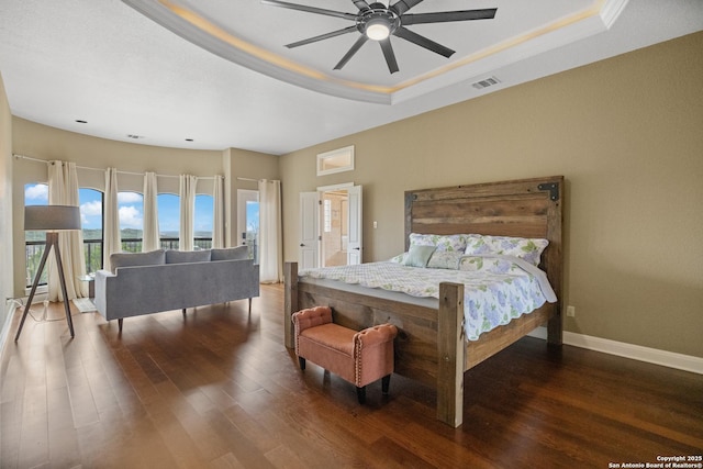 bedroom featuring dark wood-type flooring, a raised ceiling, and visible vents