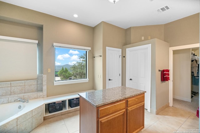 full bathroom with tiled bath, visible vents, a spacious closet, baseboards, and tile patterned floors