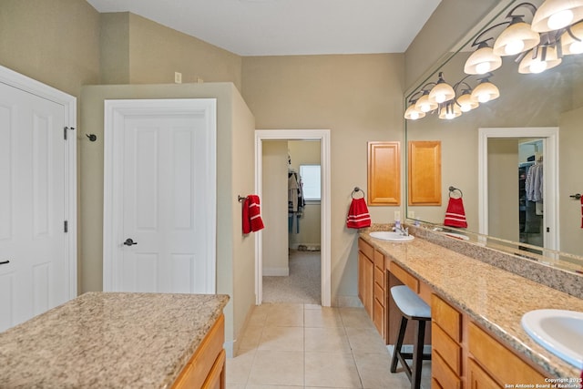 full bath featuring double vanity, a walk in closet, a sink, and tile patterned floors