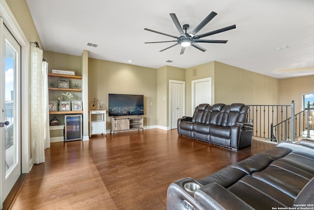 living area with a ceiling fan, baseboards, visible vents, and wood finished floors