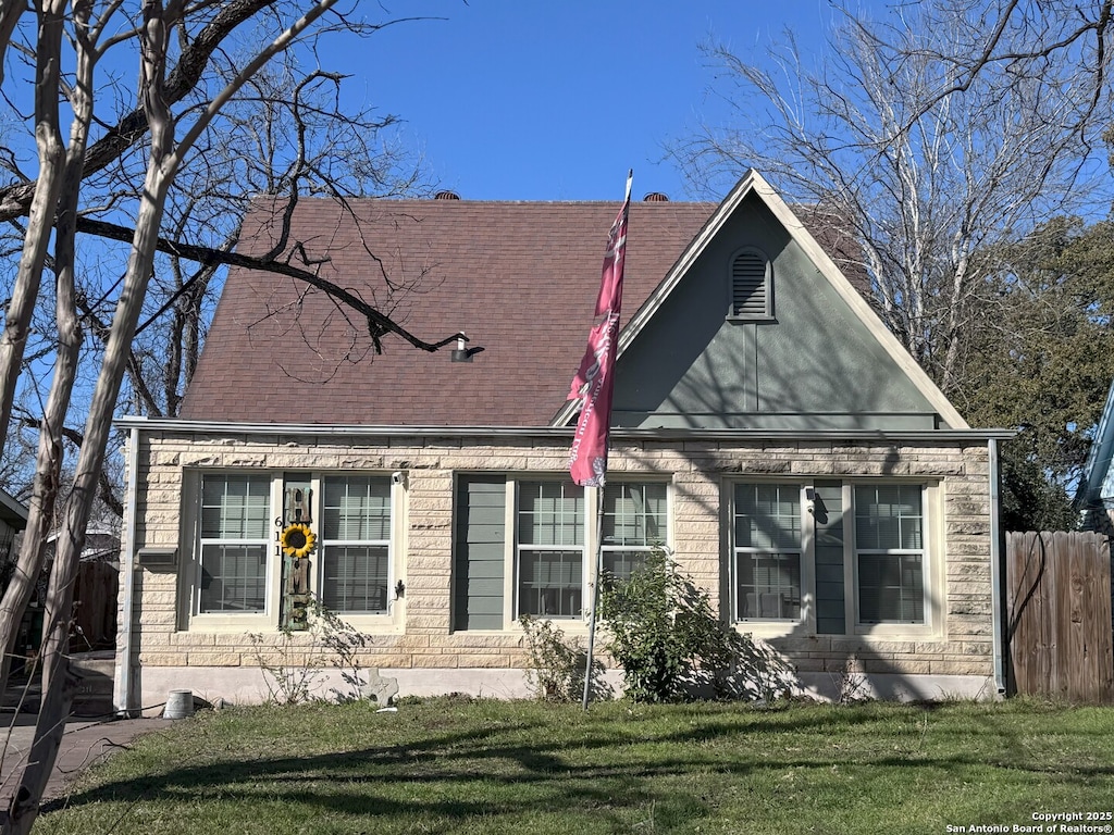 view of front of house featuring a front lawn, roof with shingles, and fence