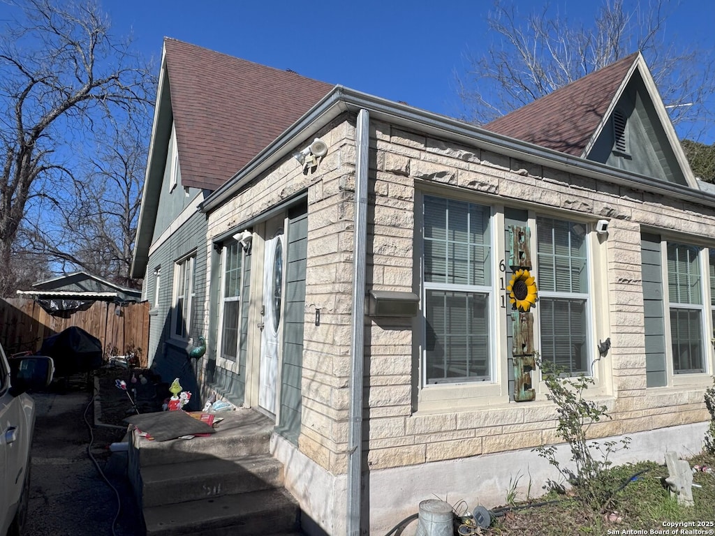 view of home's exterior featuring a shingled roof and fence