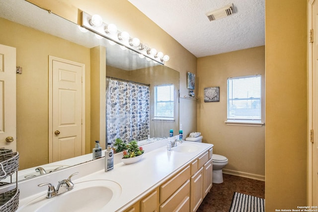 full bath with double vanity, visible vents, toilet, a sink, and a textured ceiling