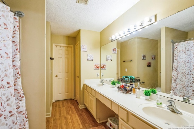 bathroom with a textured ceiling, a sink, and wood finished floors