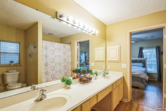 ensuite bathroom featuring toilet, ensuite bath, a sink, and wood finished floors