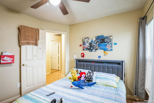 bedroom with radiator, a ceiling fan, light wood-style flooring, and baseboards