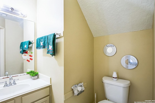 bathroom featuring vaulted ceiling, toilet, a textured ceiling, and vanity