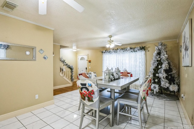 dining room featuring a ceiling fan, visible vents, crown molding, and light tile patterned floors