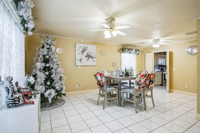 dining area with a textured ceiling, ceiling fan, light tile patterned floors, baseboards, and ornamental molding