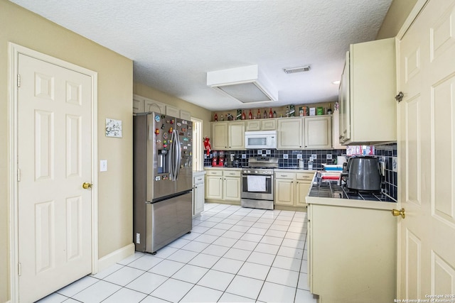 kitchen with stainless steel appliances, tile counters, visible vents, backsplash, and light tile patterned flooring