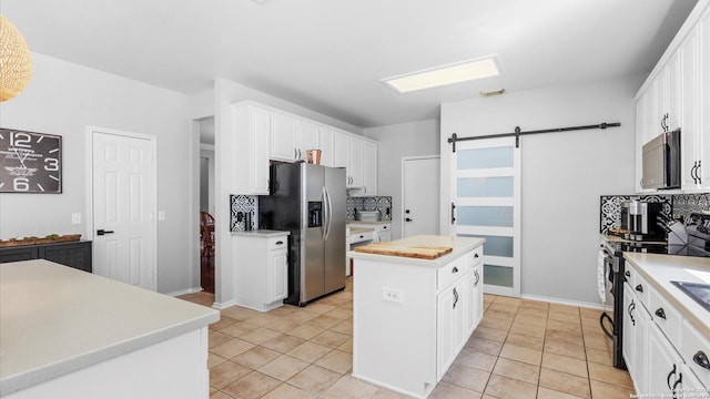 kitchen featuring a barn door, white cabinets, a kitchen island, light countertops, and stainless steel refrigerator with ice dispenser