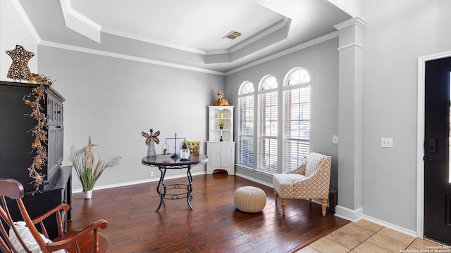 sitting room featuring a tray ceiling, visible vents, ornamental molding, wood finished floors, and ornate columns