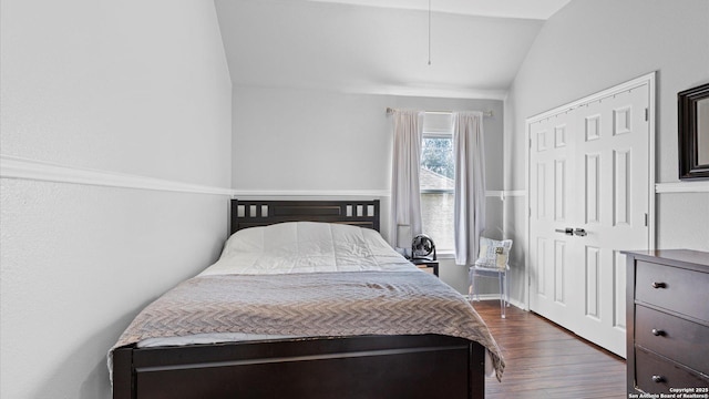 bedroom with a closet, vaulted ceiling, and dark wood-style flooring