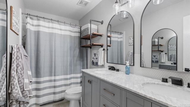 full bathroom featuring visible vents, a sink, toilet, and double vanity