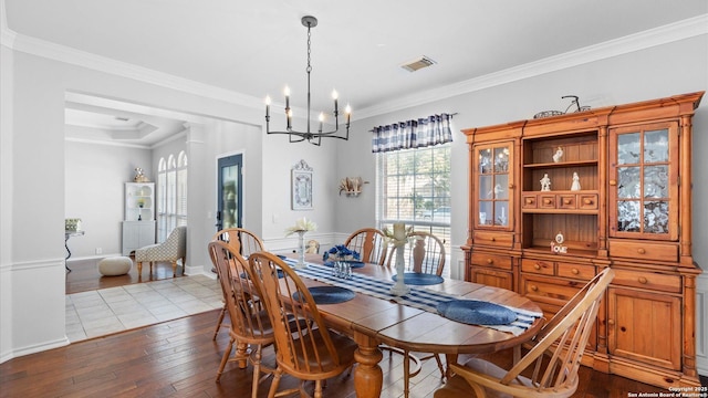 dining area with baseboards, visible vents, an inviting chandelier, crown molding, and light wood-style floors