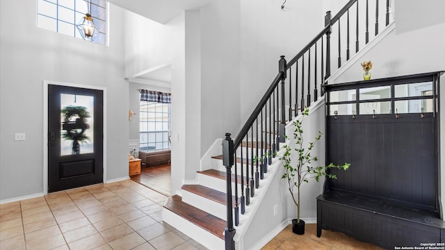 entryway featuring stairway, a towering ceiling, baseboards, and light tile patterned floors