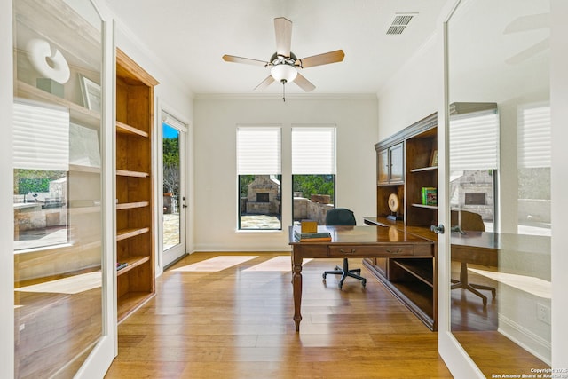 home office with light wood-style floors, ceiling fan, visible vents, and ornamental molding